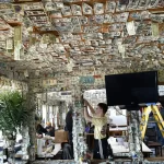 Money seems to be falling from the ceiling of Johnson Creek Tavern in 2020 as Craig Bowman, center, and volunteers remove thousands of dollar bills destined to be donated to charity. File photo by Bob Sofaly